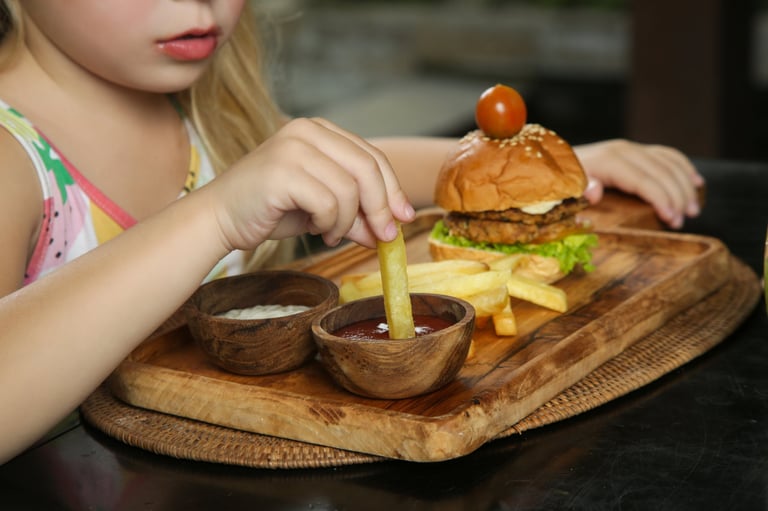 Little girl eating french fries with tomato sauce at the restaurant