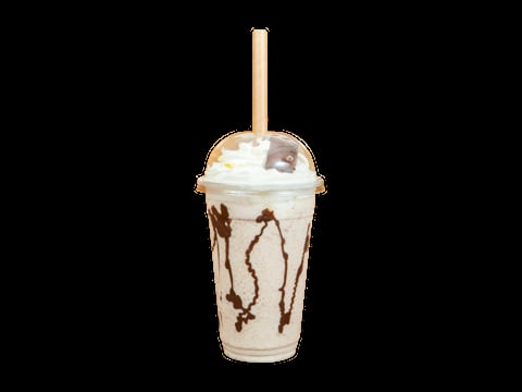 Clear plastic cup of iced latte with chocolate drizzle, whipped cream, and a wooden straw on black background