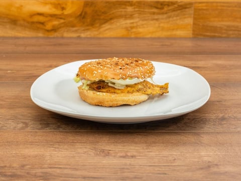 Sesame seed bagel sandwich with cheese and egg on white plate over wooden surface