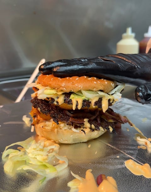Gourmet burger stacked with multiple patties, cheese, and toppings