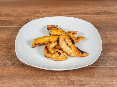 Grilled plantain slices on a white plate over a wooden surface